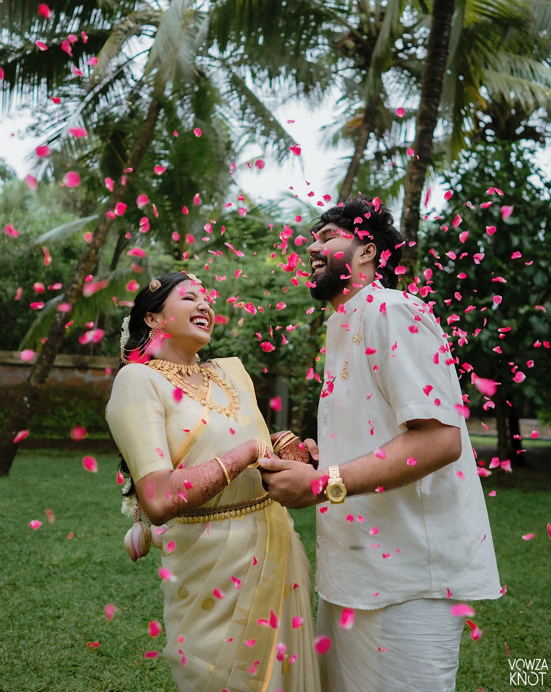 Newlyweds posing beneath red drapery and chandeliers